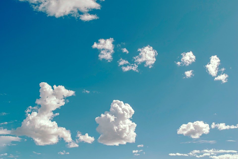 The image shows a blue sky with cumulus clouds.