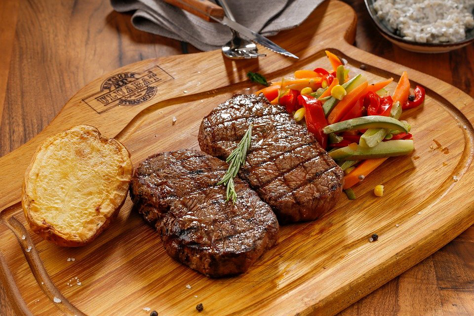 fried steak on a wooden board, garnished with vegetables.