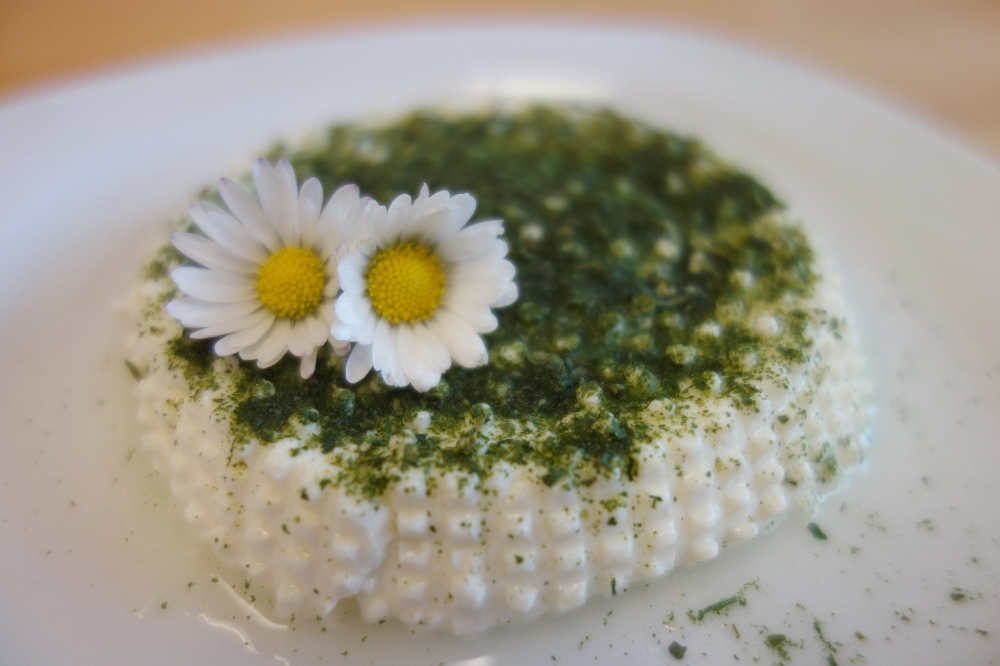Cream cheese garnished with two daisies and fresh herbs