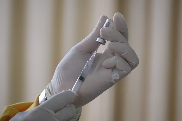 Hands holding a vaccine needle