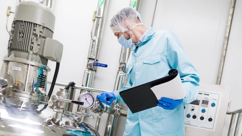 scientist in blue lab suit and gas mask look at steel tank