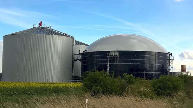 Das Bild zeigt eine Biogas-Anlage in einer ländlichen Umgebung
