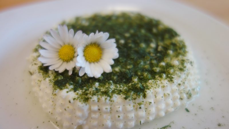 Cream cheese garnished with two daisies and fresh herbs