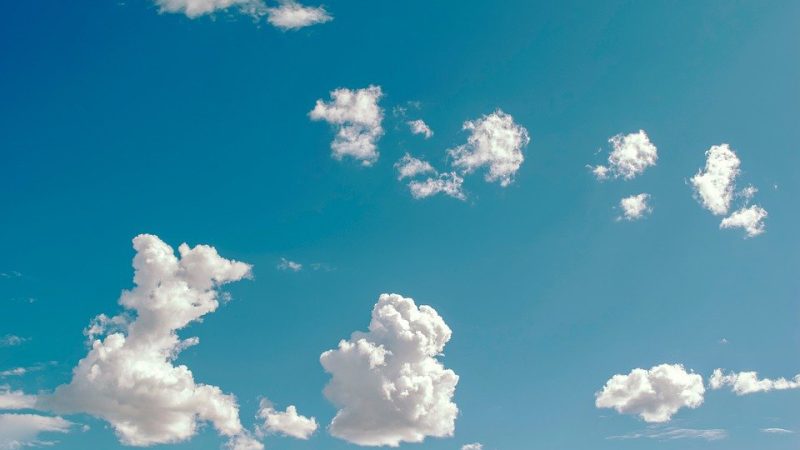 The image shows a blue sky with cumulus clouds.