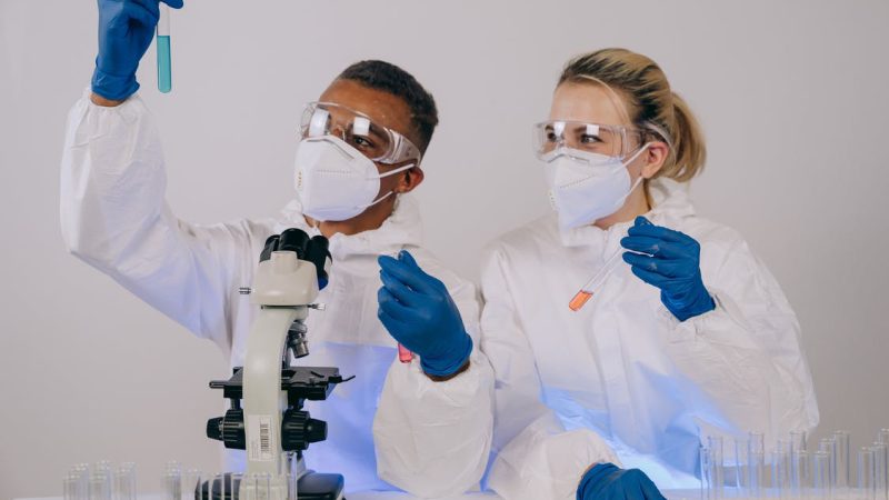 Two scientists look at a reagent vessel containing a blue liquid