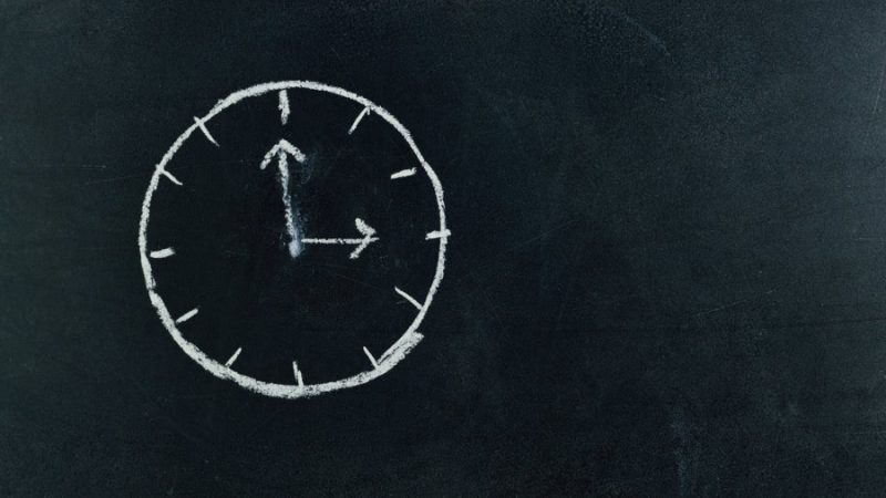 Analogue clock drawn on a blackboard with chalk