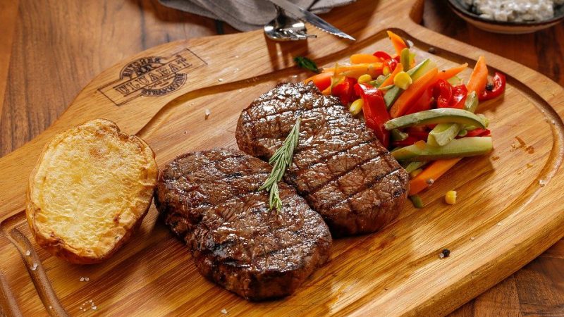 fried steak on a wooden board, garnished with vegetables.