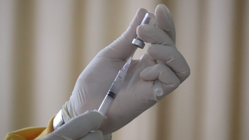 Hands holding a vaccine needle